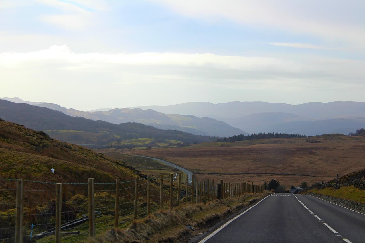 An open road running down into green hills