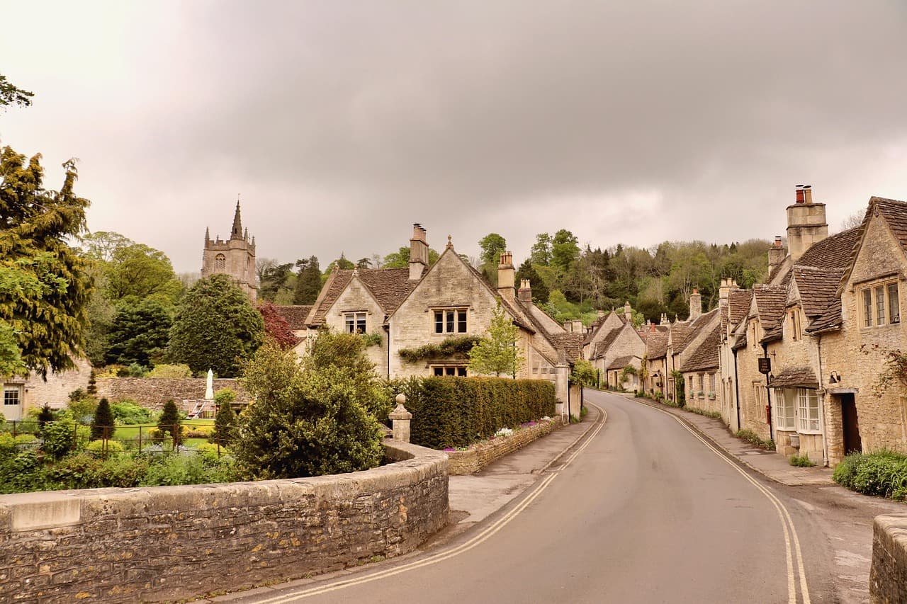 A narrow road curving through a Cotswold stone village
