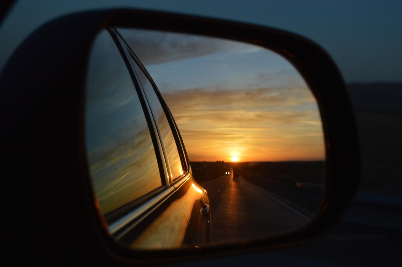 The road behind at sunset, seen in a car door mirror